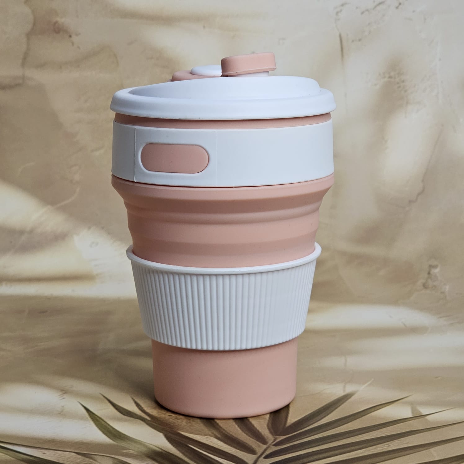 Pink and white 300ml pocket-size silicone travel coffee cup with a ridged grip and attached drinking spout cover. www.usmile.toys